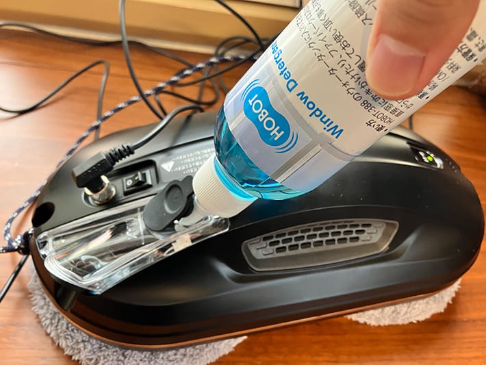 窓掃除ロボット「HOBOT」にHOBOT専用の洗剤を入れている画像