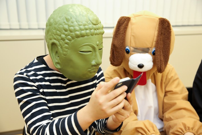 スマートフォンを覗き込む大仏さんと犬さん