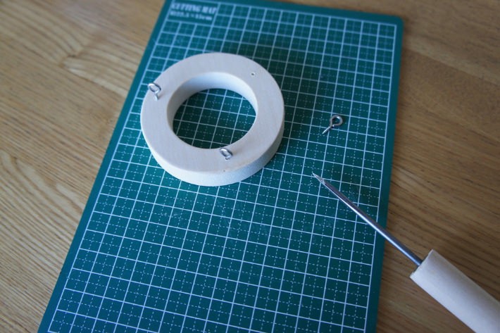 1.	ドーナツ状の木材に、キリを使って等間隔に3箇所穴を開け、そこにヒートン(金属のわっか)をねじ込みます。