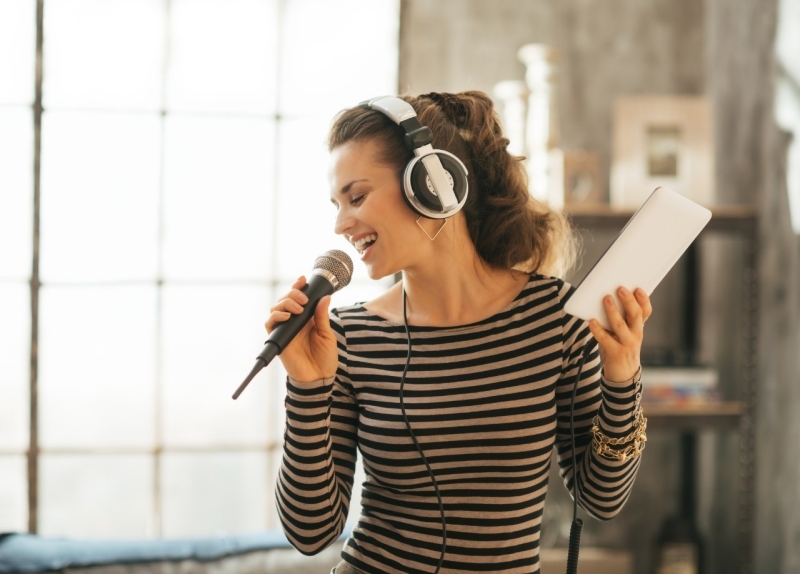 Happy young woman singing karaoke in loft apartment 活用法5:PS4ではカラオケもできる!