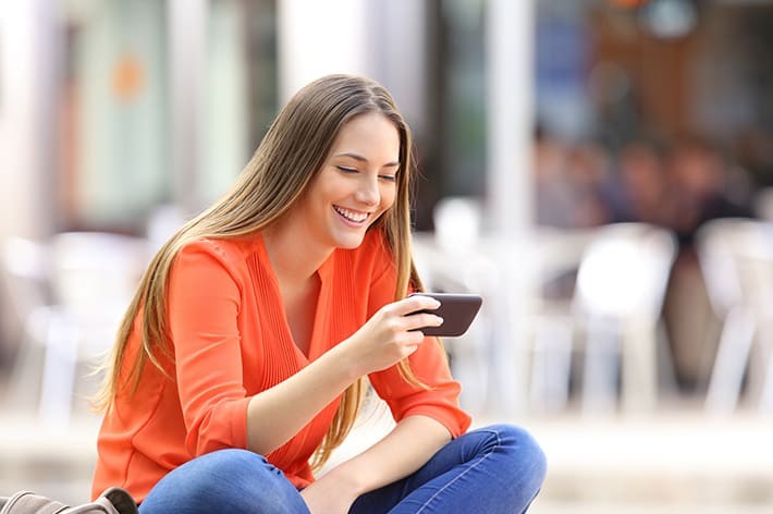 外でスマホを見ている女性