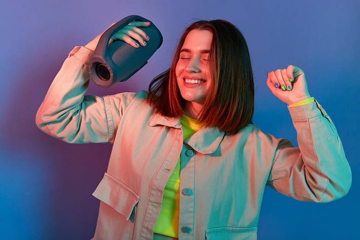 ポータブルスピーカーで音楽を聴き踊る女性